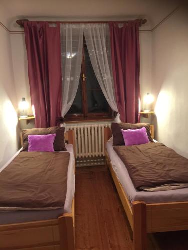 two beds in a room with purple curtains and a window at Apartmán Verona in Český Krumlov