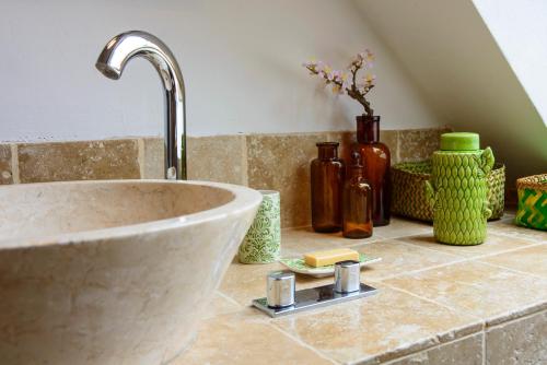 un comptoir de salle de bain avec un lavabo et quelques bouteilles dans l'établissement Maison le Village - Maison d’Hôtes, à Montagny-lès-Beaune