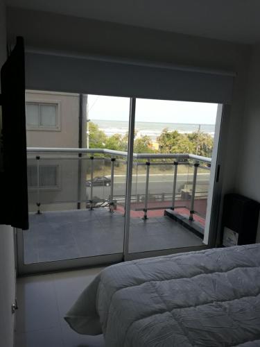 1 dormitorio con cama y vistas a un balcón en Depto frente al mar San Bernardo en San Bernardo
