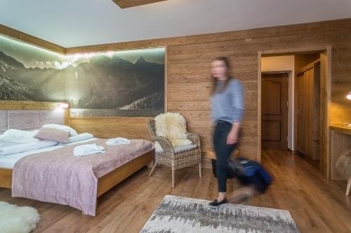 a woman is walking through a bedroom with a bed at Willa Roztoka & SPA - idealne miejsce dla Twojej rodziny in Bukowina Tatrzańska