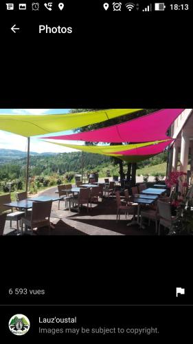 Montrodat的住宿－Lauz'oustal，露台上的五彩缤纷的遮阳伞,配有桌椅