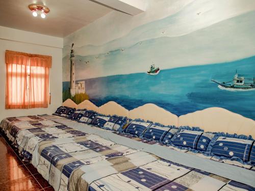 綠島鄉的住宿－綠島長泰民宿，卧室配有一张大床,墙上挂有绘画作品