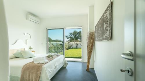 a white bedroom with a bed and a large window at Sardegna é - Villa Charme&Design in Olbia