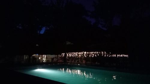 una piscina por la noche con un edificio con luces en Honey Badger Lodge, en Moshi