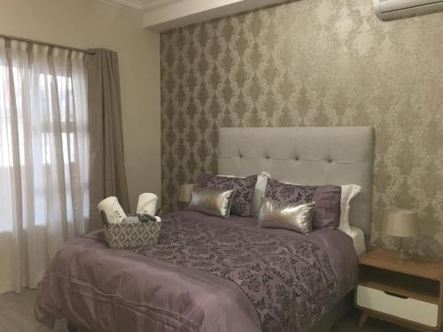 a bedroom with a large bed with a purple comforter at AYA LUXURY APARTMENTS 78 in Durban
