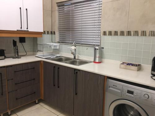 a kitchen with a sink and a washing machine at AYA LUXURY APARTMENTS 78 in Durban