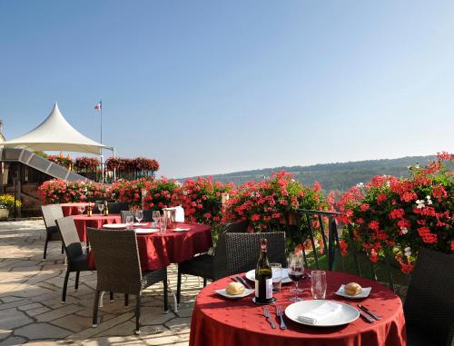 a patio with tables and chairs with red table cloths and flowers at Auberge Du Camp Romain in Chassey-le-Camp