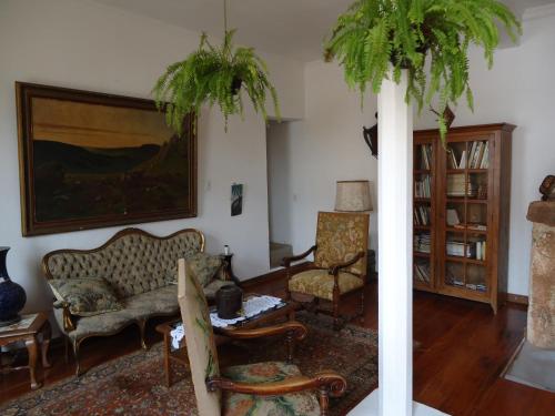a living room with two chairs and a painting at Pousada Richard Rothe in Tiradentes