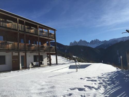 un bâtiment sur une montagne enneigée avec une piste de ski dans l'établissement Oberprantschöllhof - Horse Mountain Stable, à Bressanone