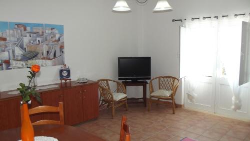 a living room with a tv and a table and chairs at Family Floripes House in Olhão