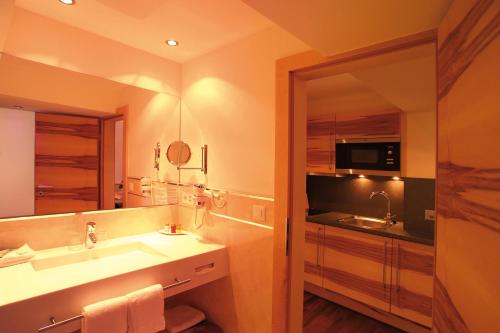 baño con lavabo y espejo grande en Hotel Garni Muttler Alpinresort & Spa, en Samnaun