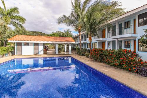 a swimming pool in front of a house with palm trees at Aquamarine 4 in Guanacaste