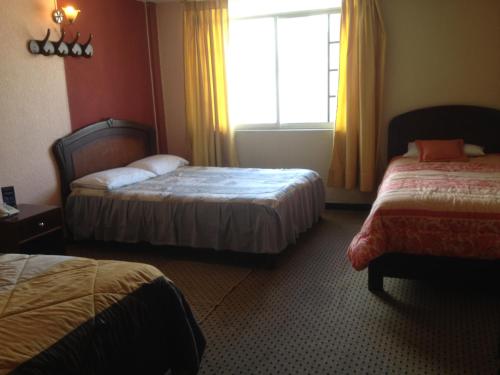 a hotel room with two beds and a window at Samana Hostal in Otavalo