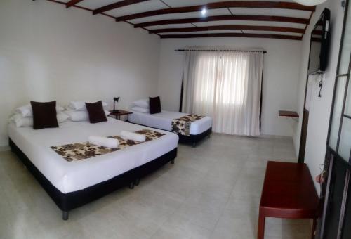 een slaapkamer met 2 bedden, een tafel en een raam bij Posada La Esperanza Boutique in Cumaral