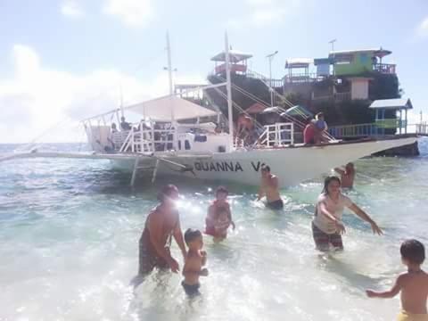 a group of people in the water in front of a boat at Guanna's Place Room and Resto Bar in Malapascua Island