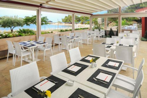 a restaurant with white tables and chairs and the ocean at Istrian Villas Plava Laguna in Umag