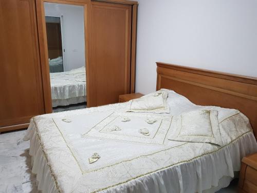 a bedroom with a white bed with a mirror at Appartement S+1 Jardin De Carthage in Tunis