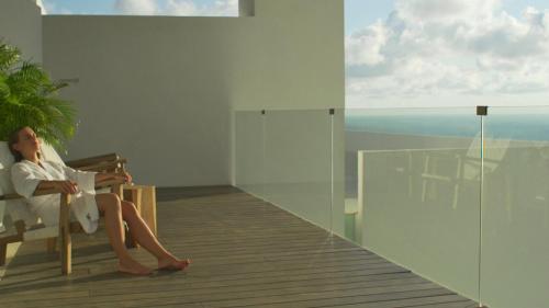 a woman sitting in a chair looking out at the ocean at Encanto Acapulco in Acapulco