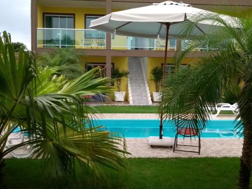 una piscina con sombrilla junto a un edificio en Residencial Alexandre, en Matinhos
