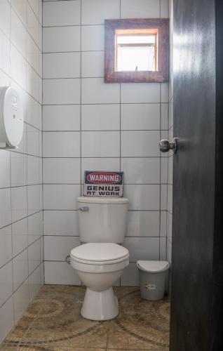 a bathroom with a toilet and a sign on the wall at Puma House in Puerto Natales