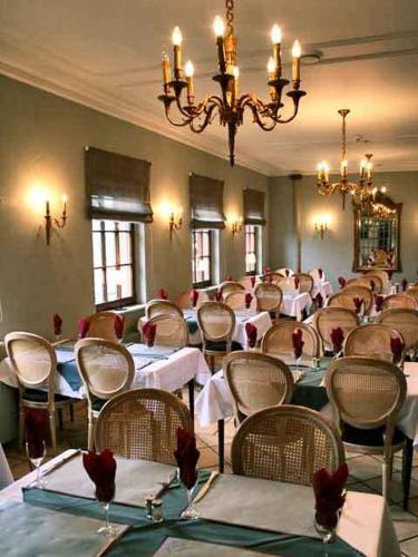 a dining room with tables and chairs and a chandelier at Hotel Castello Borghese in Senningerberg