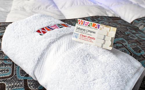 a white towel with a sign on a bed at Wifala Thematic Hotel Boutique in Cusco