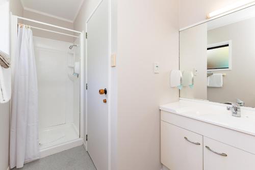 a white bathroom with a sink and a mirror at Outrigger Motel in Paihia