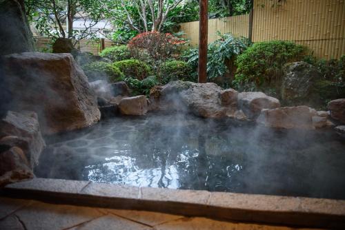 a pool of water with rocks in a garden at Yunohira Kamiyanagiya in Yufuin