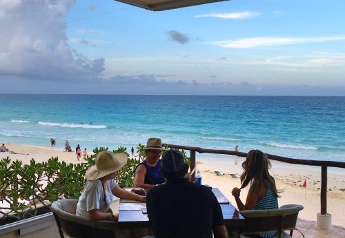 a group of people sitting at a table on the beach at Cancun Plaza - Best Beach in Cancún