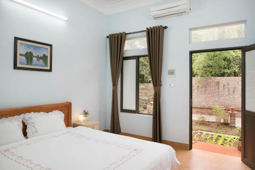 a bedroom with a white bed and two windows at Tam Coc Craft Homestay in Ninh Binh
