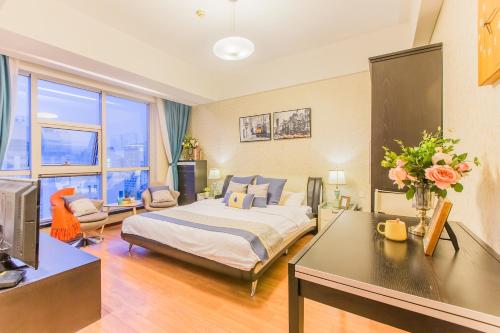 a hotel room with a bed and a desk with flowers at Westlake 7 Service Apartment in Hangzhou