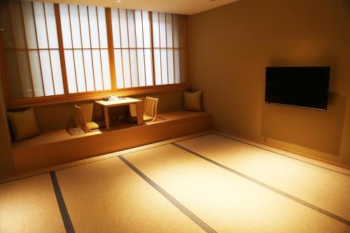 a room with a television and a table in front of a window at Chiayi Maison de Chine Hotel in Chiayi City