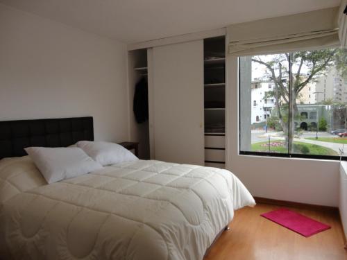 a bedroom with a large bed and a large window at Miraflores Bello Apartamento in Lima