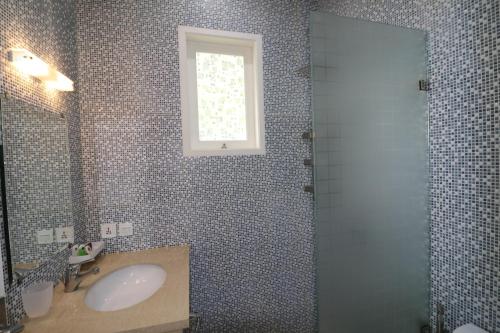 La salle de bains est pourvue d'un lavabo, d'une douche et d'une fenêtre. dans l'établissement Diyar Villas Puncak M6-11, à Puncak