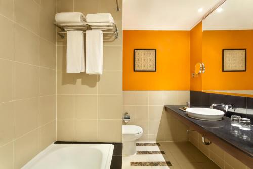 a bathroom with a toilet and a sink at Novotel Semarang in Semarang