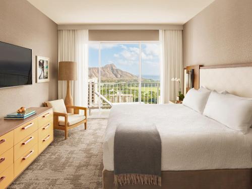 a hotel room with a bed and a large window at 'Alohilani Resort Waikiki Beach in Honolulu