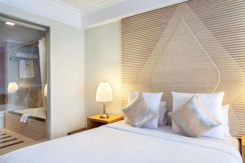 a bedroom with a large white bed with pillows at Novotel Semarang in Semarang