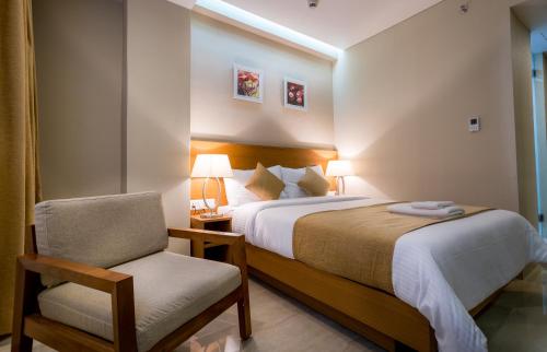 a hotel room with a bed and a chair at Classic Grande,a Member of Radisson in Imphal