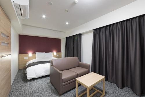 a hotel room with a bed and a chair at Dormy Inn Matsuyama Natural Hot Spring in Matsuyama
