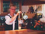 a woman in a kitchen with a coffee machine at Hotel Landgut Ochsenkopf in Rotta