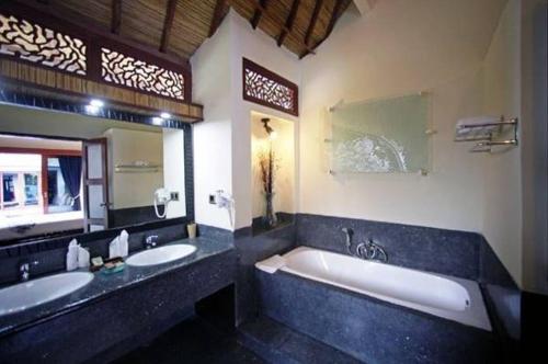 La salle de bains est pourvue de 2 lavabos et d'une grande baignoire. dans l'établissement Luce d'Alma Suites Resort & Spa, à Gili Trawangan