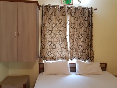 a bedroom with a bed with two pillows and a window at Comfort`s Pearl in Coimbatore