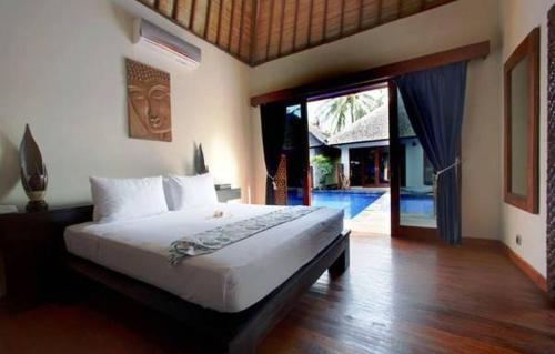 1 dormitorio con 1 cama y puerta corredera de cristal en Luce d'Alma Suites Resort & Spa, en Gili Trawangan