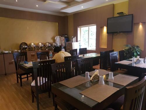 um restaurante com mesas e cadeiras e uma pessoa sentada à mesa em SBS Grand em Coimbatore