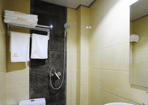a bathroom with a shower and a toilet and towels at JUNYI Hotel Guizhou Guiyang Bageyan Road in Guiyang