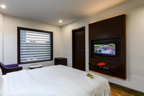 a bedroom with a white bed and a flat screen tv at Howard Johnson by Wyndham, Kolkata Airport in Kolkata