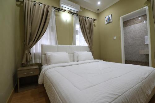 a bedroom with a large white bed and a window at Diyar Villas Puncak M6/12 in Puncak