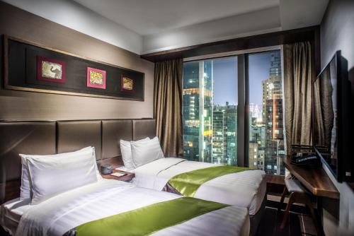 a hotel room with two beds and a window at Soravit on Granville in Hong Kong