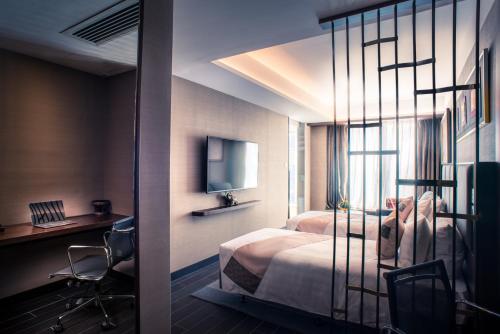 a bedroom with a bed and a desk and a television at Soravit on Granville in Hong Kong