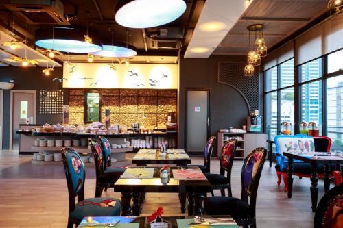 a restaurant with tables and chairs and a counter at Hotel Clover Asoke - SHA Extra Plus in Bangkok